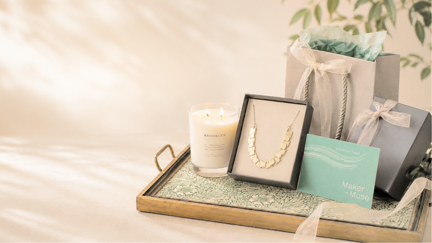 Tray with jewelry, candle, and gift boxes on a soft background